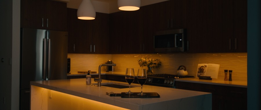 A kitchen illuminated by dim, amber lighting through a smart home lighting system. 