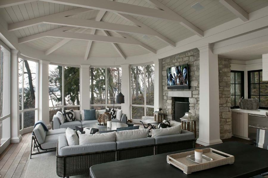 A sunroom with in-ceiling speakers and a TV above a fireplace.