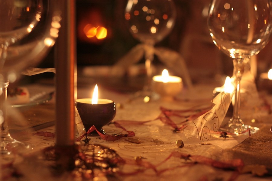 A close-up of a holiday table illuminated by candles.